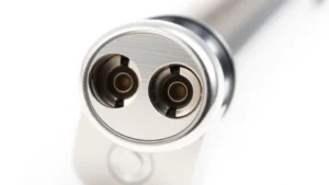 Close-up of a stainless steel dual-hole cosmetic pencil sharpener with sharp blades, showing precision engineering details and metallic finish against white background