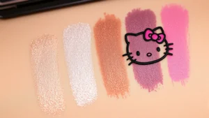 Photorealistic close-up of Hello Kitty brand eyeshadow palette swatches displayed on light skin tone, showing multiple shimmer and matte finishes with rich pigmentation, professional lighting highlighting texture and color payoff, beauty photography style
