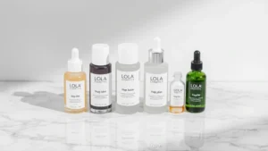 Lola Cosmetics skincare serums and moisturizers arranged on marble surface with water droplets, minimal aesthetic, professional product photography