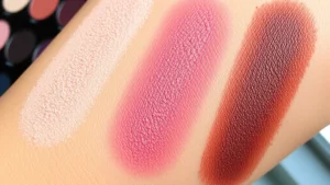 Close-up of vibrant eyeshadow palette swatches on fair, medium, and deep skin tones showing pigmentation and blendability in natural window lighting