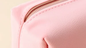 Close-up of luxury velour cosmetic bag texture in soft pink, showing fine material details and stitching quality, professional product photography with neutral background